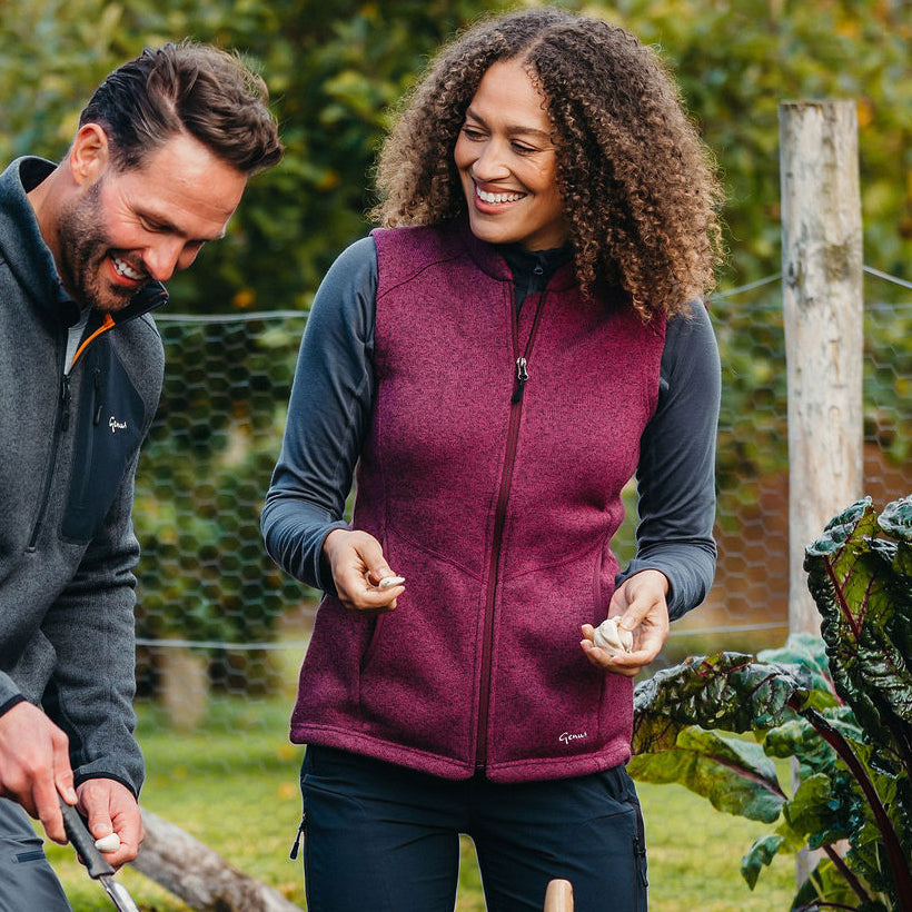 Women wearing a Genus Grape Dixter Gardening Gilet in her garden