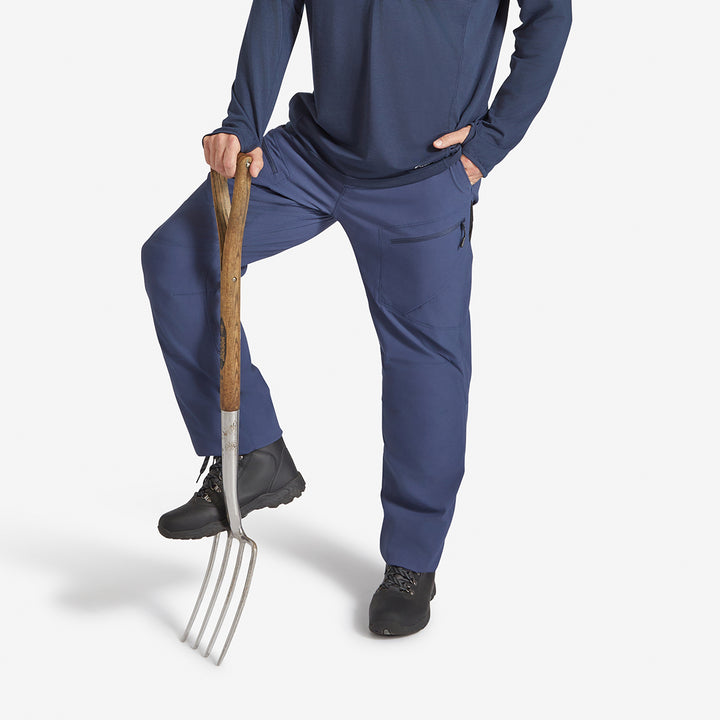 Man holding a gardening fork wearing a Genus Men's Marine Blue Eden Zip Neck Top 