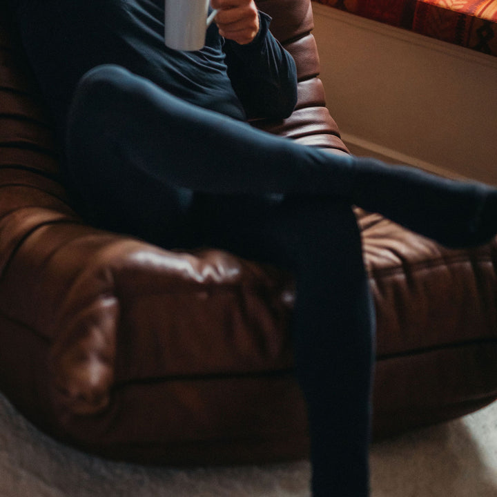 Man on a sofa in the Genus Men's Merino Blend Thermal Leggings