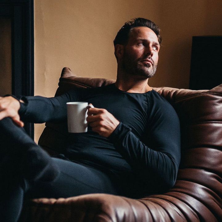Man on a sofa wearing the Genus Men's Merino Blend Thermal Top