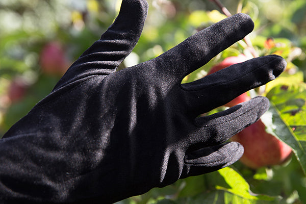 Genus silk gardening gloves on a person's hand in a garden